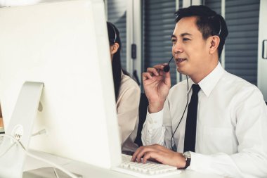 Kulaklık takan bir işadamı aktif olarak ofiste çalışıyor.