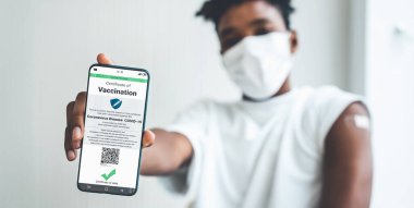 Afrikalı Amerikalı genç cep telefonunda aşı pasaportu gösteriyor