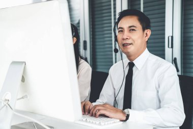 Kulaklık takan bir işadamı aktif olarak ofiste çalışıyor.