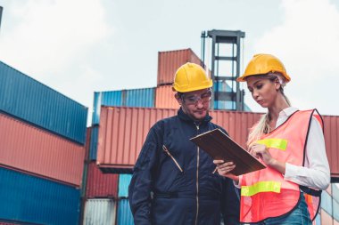 Endüstriyel işçiler, deniz aşırı nakliye konteynır sahasında iş arkadaşlarıyla çalışıyor.