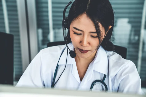 Médico usando fone de ouvido falando ativamente em videochamada no hospital ou na clínica — Fotografia de Stock