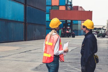 Endüstriyel işçiler, deniz aşırı nakliye konteynır sahasında iş arkadaşlarıyla çalışıyor.