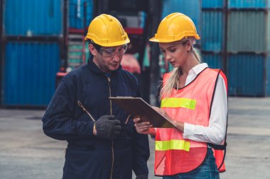 Endüstriyel işçiler, deniz aşırı nakliye konteynır sahasında iş arkadaşlarıyla çalışıyor.