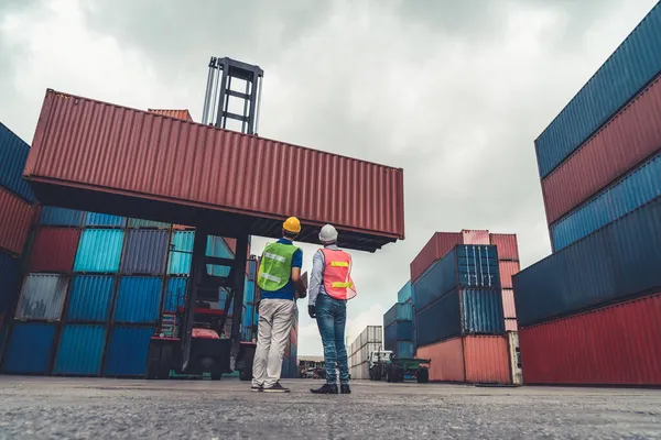 Pracownik przemysłu współpracuje ze współpracownikiem w zagranicznej stoczni kontenerowej — Zdjęcie stockowe
