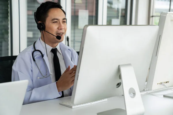 Medico indossando auricolare parlando attivamente in videochiamata in una clinica o in ospedale . — Foto Stock