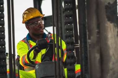 Tersanede forklift kullanan Afrikalı Amerikalı bir adam.