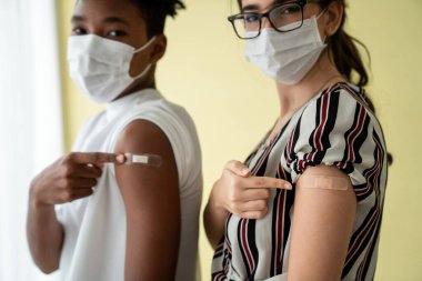 COVID-19 aşısı gösteren bir grup insan neşeyle sargılanıyor.