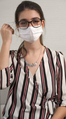 Genç bir kadın yüzünden maskesini çıkarıyor.