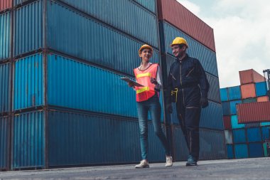 Endüstriyel işçiler, deniz aşırı nakliye konteynır sahasında iş arkadaşlarıyla çalışıyor.