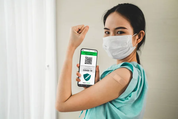 Mujer asiática joven muestra pasaporte de vacuna en el teléfono móvil —  Fotos de Stock
