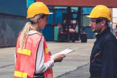 Endüstriyel işçiler, deniz aşırı nakliye konteynır sahasında iş arkadaşlarıyla çalışıyor.