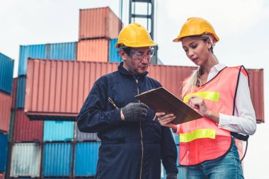 Endüstriyel işçiler, deniz aşırı nakliye konteynır sahasında iş arkadaşlarıyla çalışıyor.