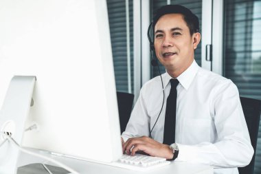 Kulaklık takan bir işadamı aktif olarak ofiste çalışıyor.