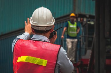 Endüstriyel işçiler, deniz aşırı nakliye konteynır sahasında iş arkadaşlarıyla çalışıyor.
