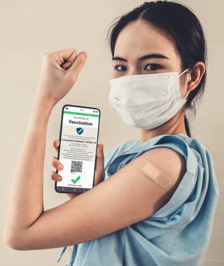 Genç Asyalı kadın cep telefonunda aşı pasaportu gösteriyor.