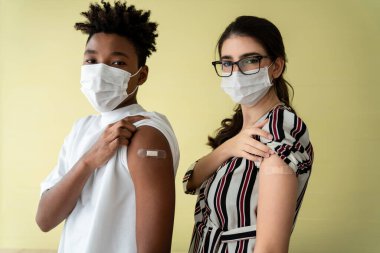 COVID-19 aşısı gösteren bir grup insan neşeyle sargılanıyor.