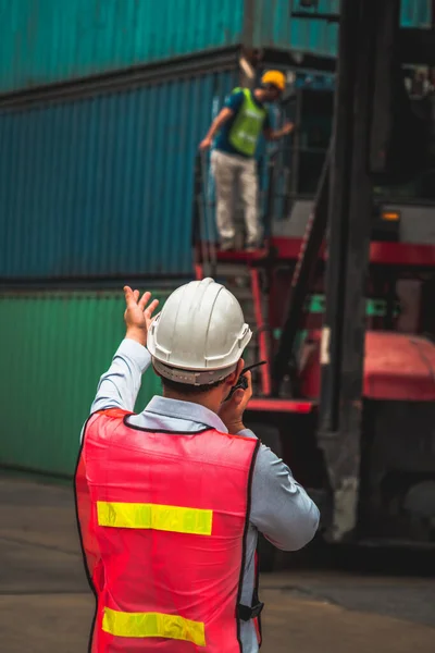 Trabajador industrial trabaja con su compañero de trabajo en el patio de contenedores de envío en el extranjero — Foto de Stock