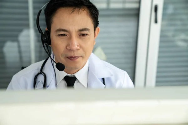 Orvos visel headset beszél aktívan videohívás egy klinikán vagy kórházban . — Stock Fotó