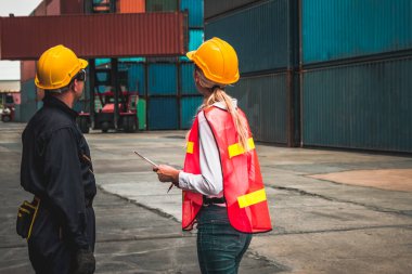 Endüstriyel işçiler, deniz aşırı nakliye konteynır sahasında iş arkadaşlarıyla çalışıyor.
