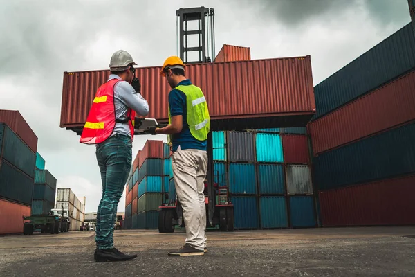 Trabajador industrial trabaja con su compañero de trabajo en el patio de contenedores de envío en el extranjero — Foto de Stock