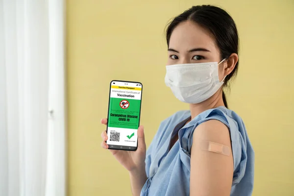 Junge Asiatin zeigt Impfpass auf Handy — Stockfoto