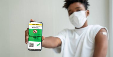 Afrikalı Amerikalı genç cep telefonunda aşı pasaportu gösteriyor