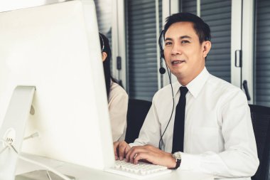 Kulaklık takan bir işadamı aktif olarak ofiste çalışıyor.