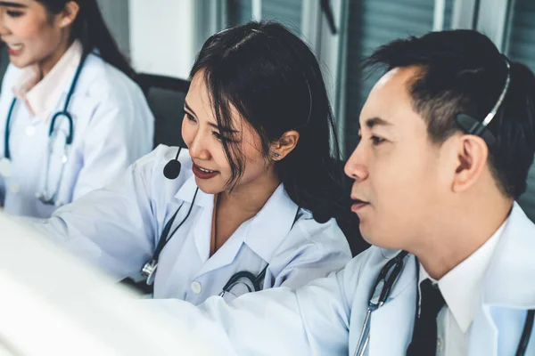 Equipe médica usando fone de ouvido conversando ativamente em videochamada na clínica do hospital — Fotografia de Stock