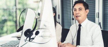 Kulaklık takan bir işadamı aktif olarak ofiste çalışıyor.