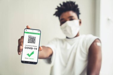 Afrikalı Amerikalı genç cep telefonunda aşı pasaportu gösteriyor