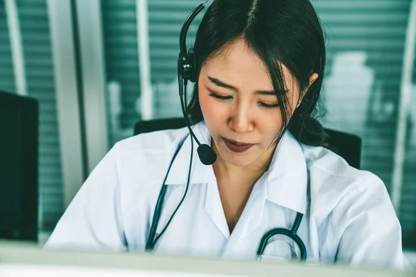 Médico usando fone de ouvido falando ativamente em videochamada no hospital ou na clínica — Fotografia de Stock