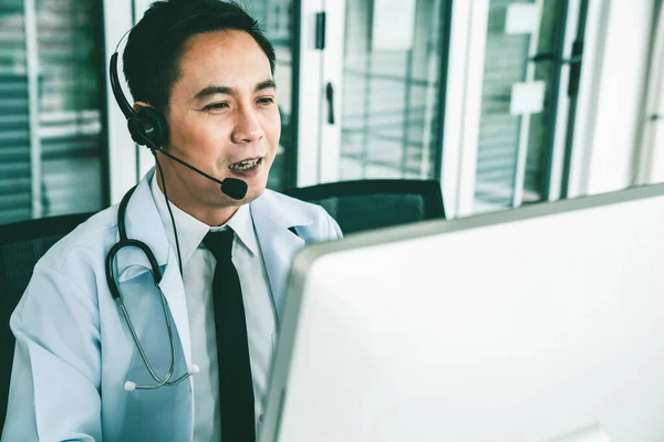 Medico indossando auricolare parlando attivamente in videochiamata in una clinica o in ospedale . — Foto Stock