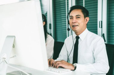 Kulaklık takan bir işadamı aktif olarak ofiste çalışıyor.