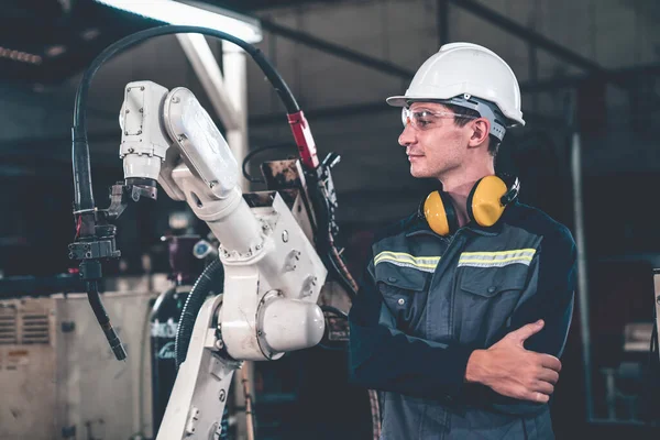 Ung fabriksarbetare som arbetar med adept robotarm — Stockfoto