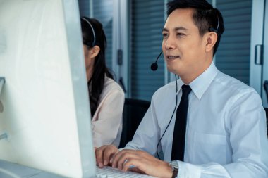 Kulaklık takan bir işadamı aktif olarak ofiste çalışıyor.