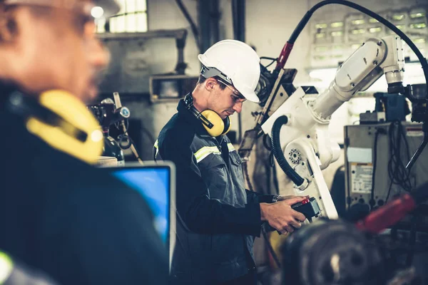 Trabajadores de la fábrica que trabajan con un brazo robótico experto en un taller —  Fotos de Stock