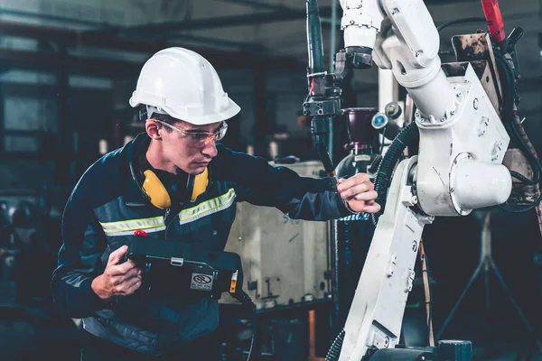Ung fabriksarbetare som arbetar med adept robotarm — Stockfoto