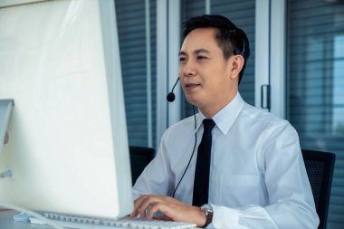 Kulaklık takan bir işadamı aktif olarak ofiste çalışıyor.