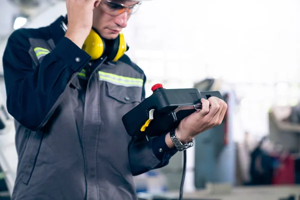 Jeune ouvrier d'usine travaillant avec un bras robotique compétent — Photo