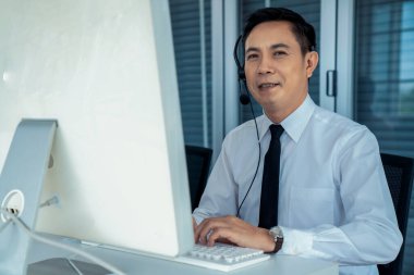 Kulaklık takan bir işadamı aktif olarak ofiste çalışıyor.