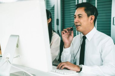 Kulaklık takan bir işadamı aktif olarak ofiste çalışıyor.