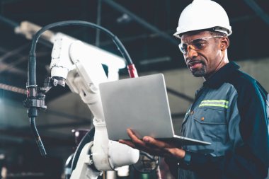 Uzman robotik kolla çalışan Afrikalı Amerikalı fabrika işçisi