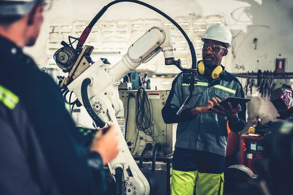 Fabriksarbetare som arbetar med adept robotarm i en verkstad — Stockfoto