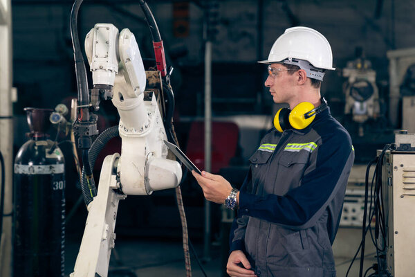 Young factory worker working with adept robotic arm