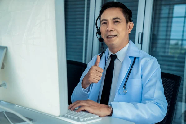 Medico indossando auricolare parlando attivamente in videochiamata in una clinica o in ospedale . — Foto Stock