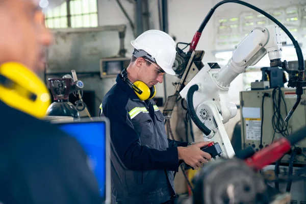 Fabrika işçileri bir atölyede usta robot kolla çalışıyorlar. — Stok fotoğraf
