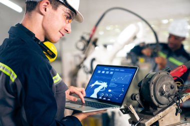 Genç fabrika işçisi usta bir robot kolla çalışıyor.