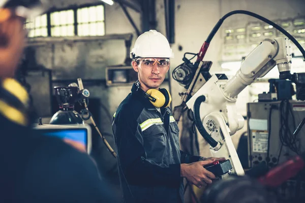 Pracownicy fabryki pracujący z robotycznym ramieniem wwarsztacie — Zdjęcie stockowe