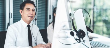 Kulaklık takan bir işadamı aktif olarak ofiste çalışıyor.