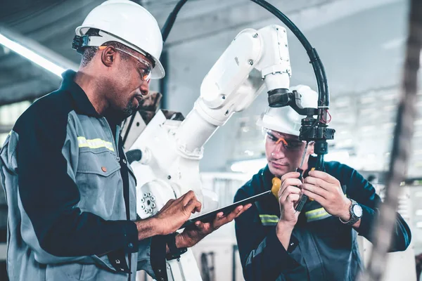 Travailleurs d'usine travaillant avec un bras robotique adepte dans un atelier — Photo